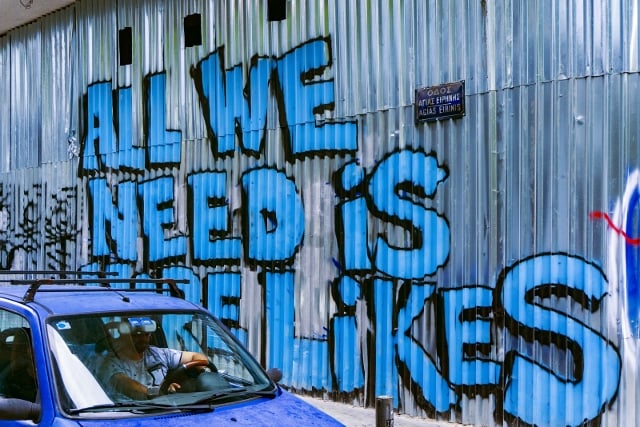 graffiti on sheet metal wall that says 'all we need is more likes'