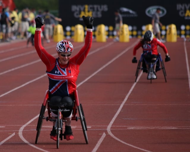 person in wheelchair crossing finish line victoriously
