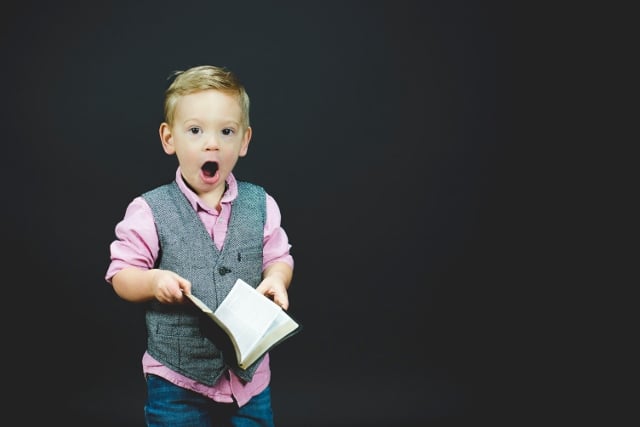 toddler holding book saying 'um'