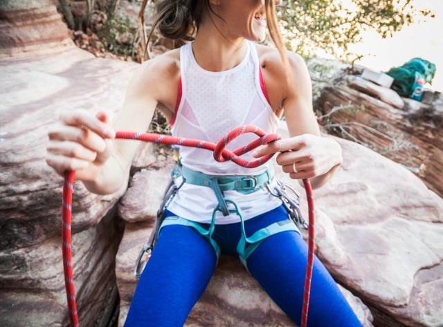 smiling woman tying climbing knot