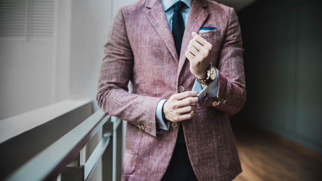 stylish person in red jacket adjusting cuffs on dress shirt