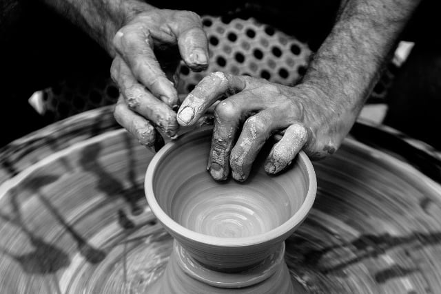 hands shaping pottery on a potter's wheel