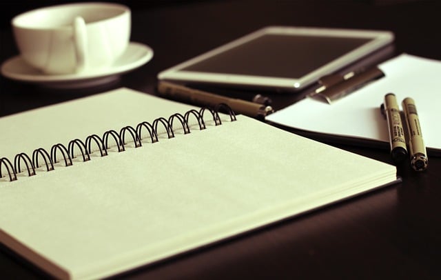 open notebook in front of tea cup and pens