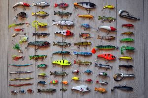 array of fishing hooks and lures arranged on wooden background