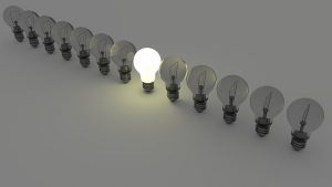 single lightbulb lit in a row of dim bulbs