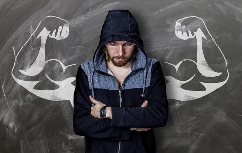 writer thinking of strong words in front of chalkboard drawing of muscular arms