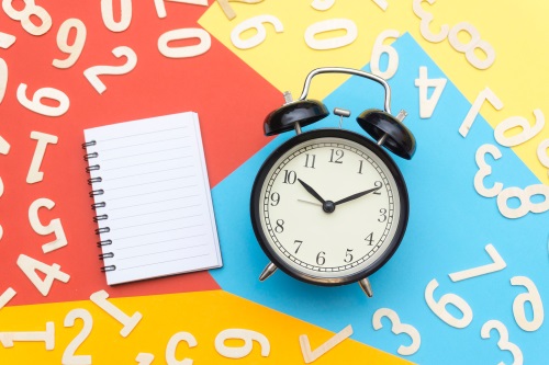 alarm clock and school notebook surrounded by numbers