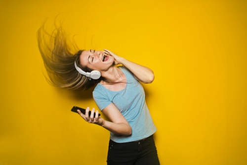 young woman dancing listening to music with happy tone through headphones