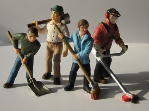 four plastic action figures posing with tools and brooms