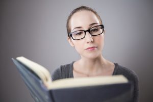 woman with glasses reading book before paraphrasing