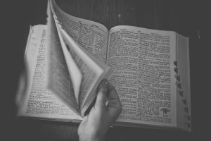 black and white image of hand flipping through dictionary pages