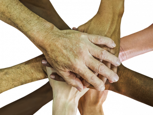 stacked hands of numerous ages and skin colors