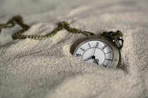 vintage pocket watch partially buried in sand