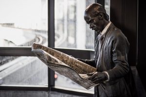 statue of man reading a newspaper