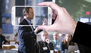 authoritative man framed by smart phone screen while speaking