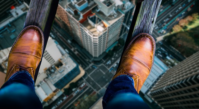 feet balancing on wooden ledge above city