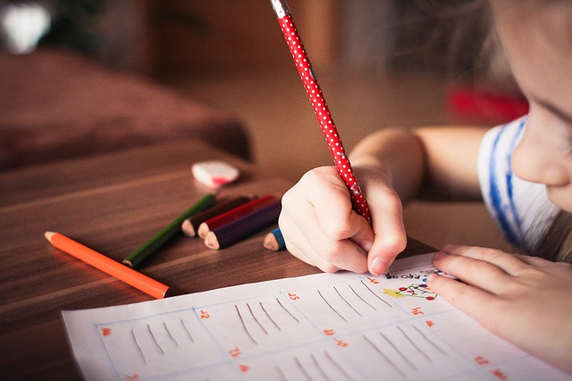 young child doing homework with pencils