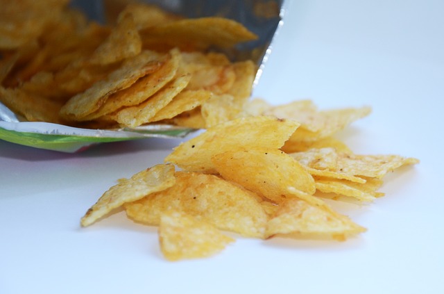 open bag of potato chips spilling onto surface